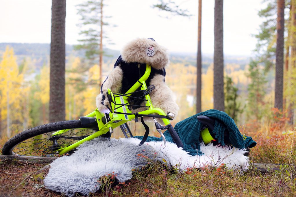 Kaupunkipyörä metsässä taljan päällä karvahattu päässä.