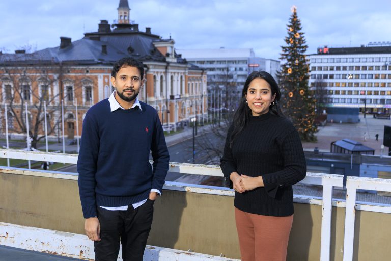 Kaksi henkilöä parvekkeella kaupungintalon edustalla.