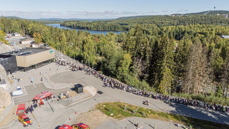 Ihmisjoukko vaeltaa Luolaan. Ympärillä metsä ja järvi.